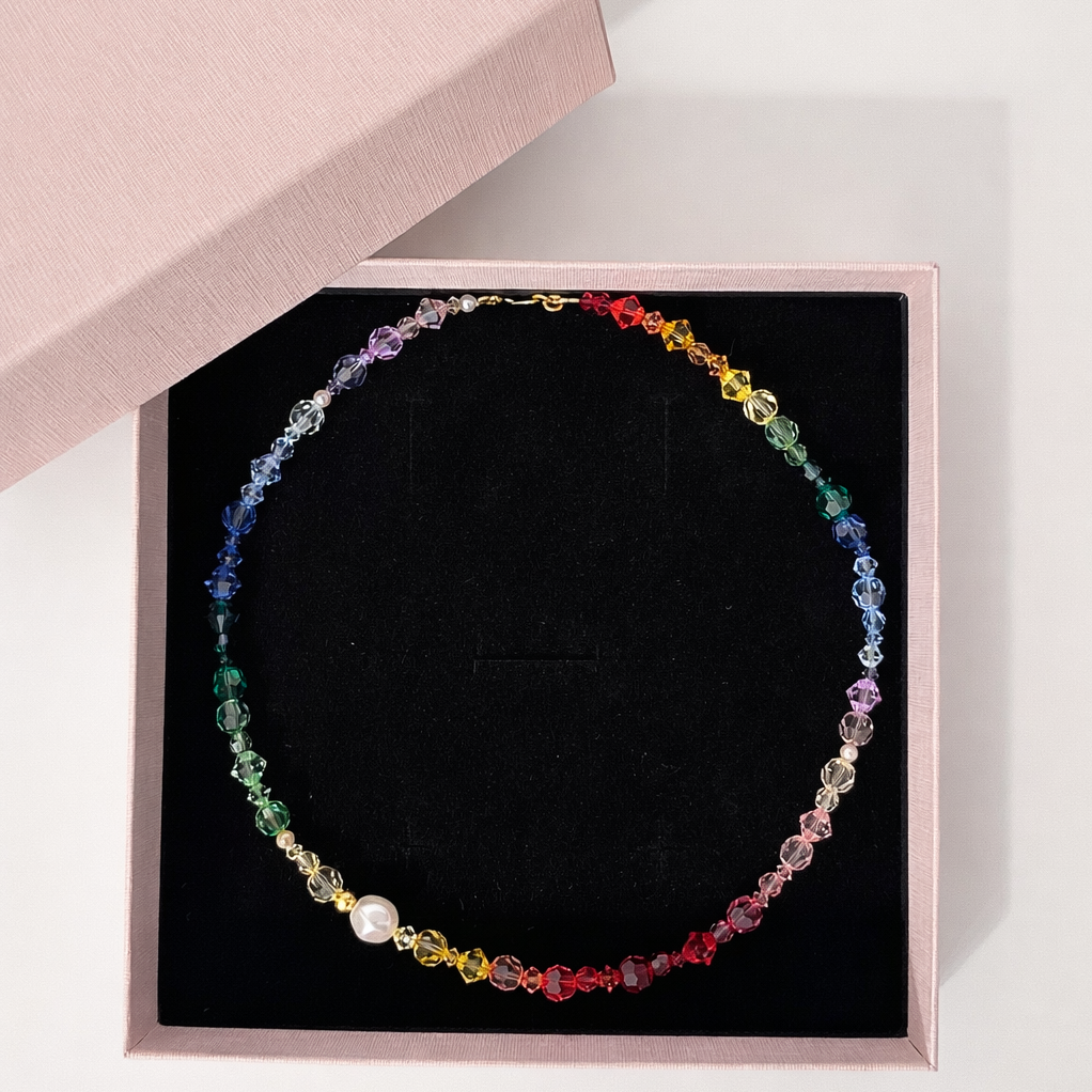 collana in colori dell'arcobaleno con perline nel packaging rosa