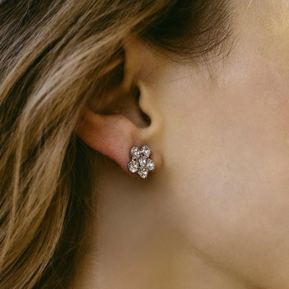 orecchini a fiorellino indossato a lobo con capelli sciolti castani