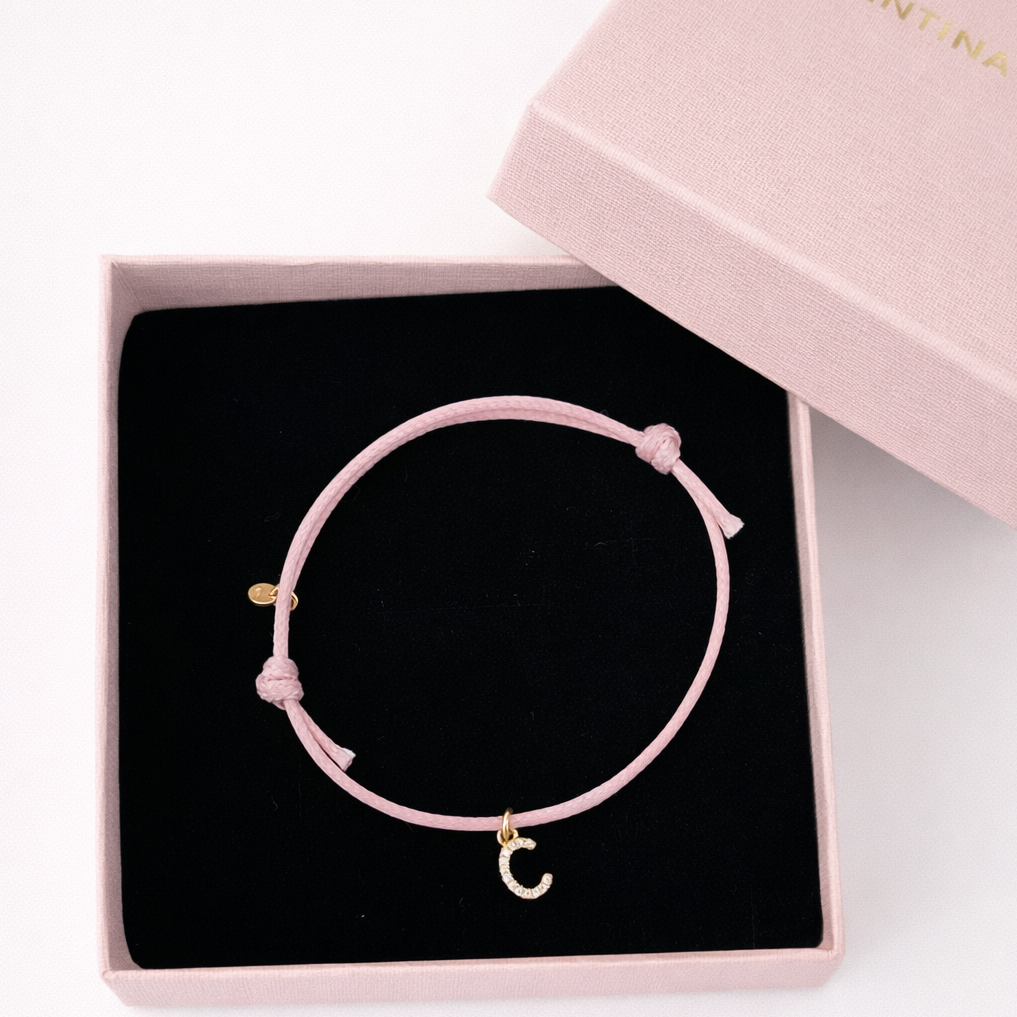 bracciale rosa con cordino e lettera con zirconi e rifiniture oro in scatola rosa 