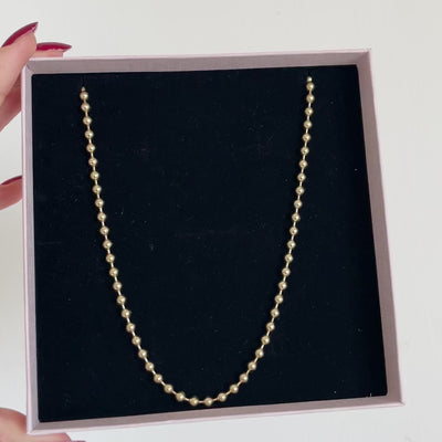 collana con catenina di sfere oro in packaging rosa luminoso